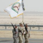 U.S. military soldiers carry the flag of the United States Central Command at the beginning of a military parade in Subiya, Kuwait